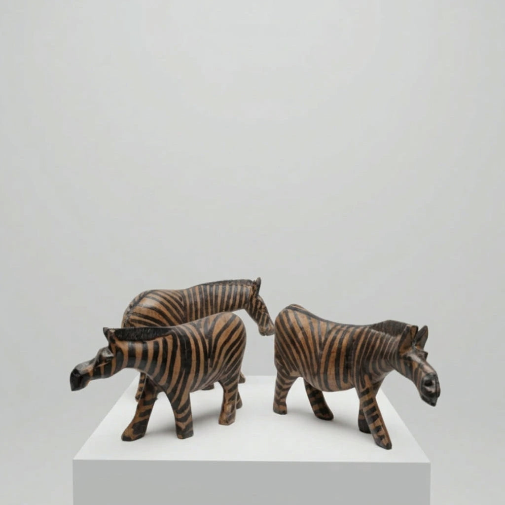 3 wooden african zebra sculptures on a plinth