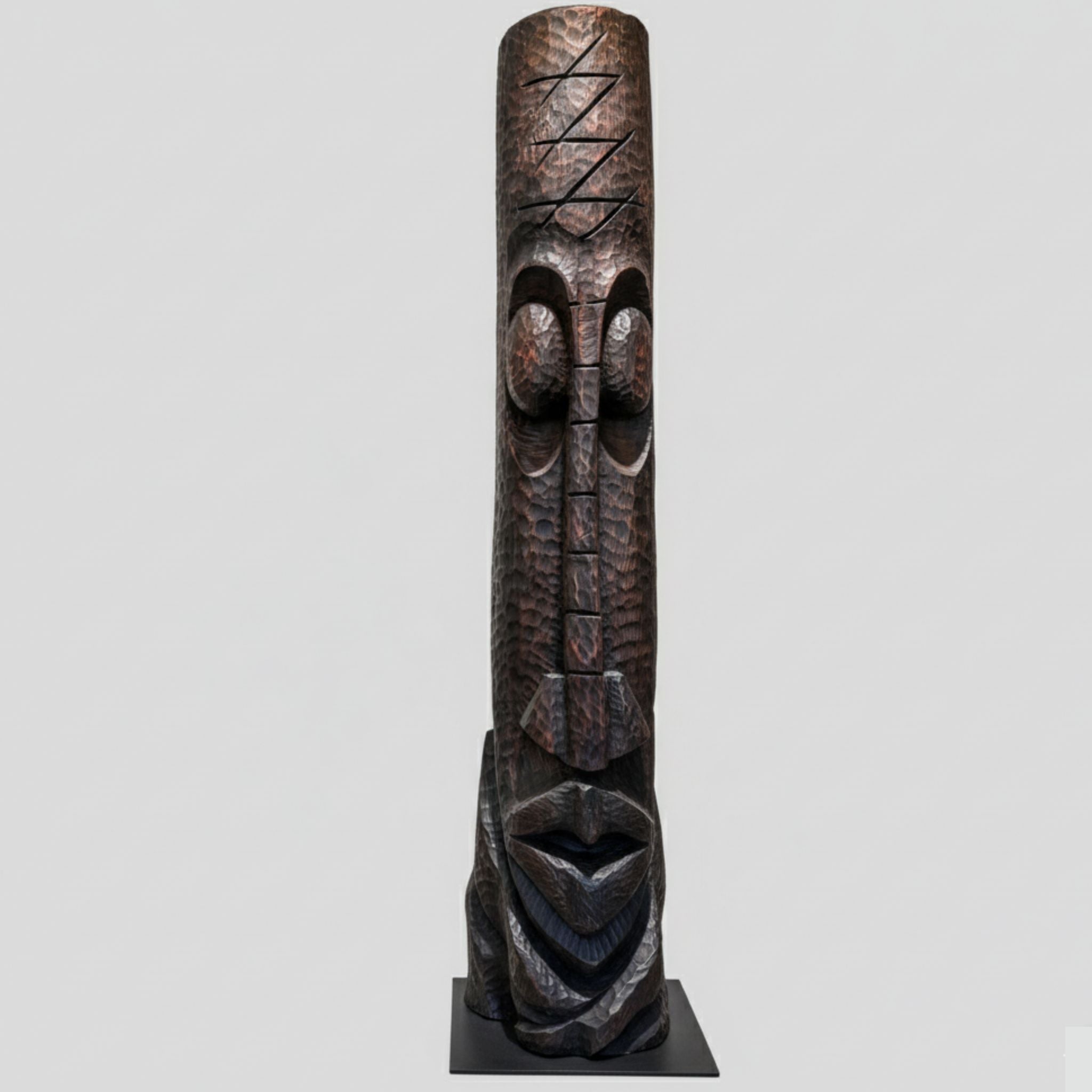 Wooden totem sculpture with carvings on a gray background
