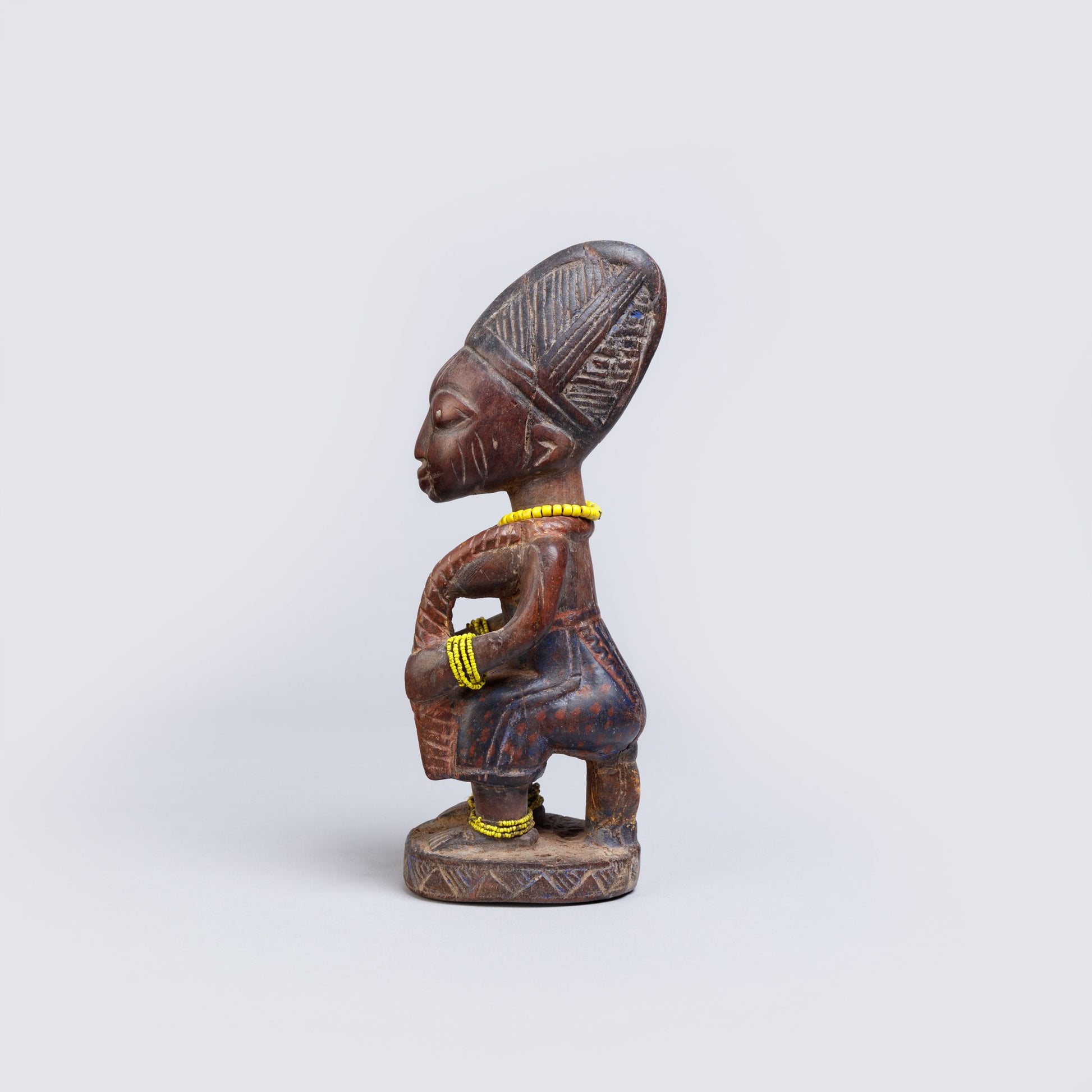 Wooden figurine of a seated figure with intricate carvings on a white background