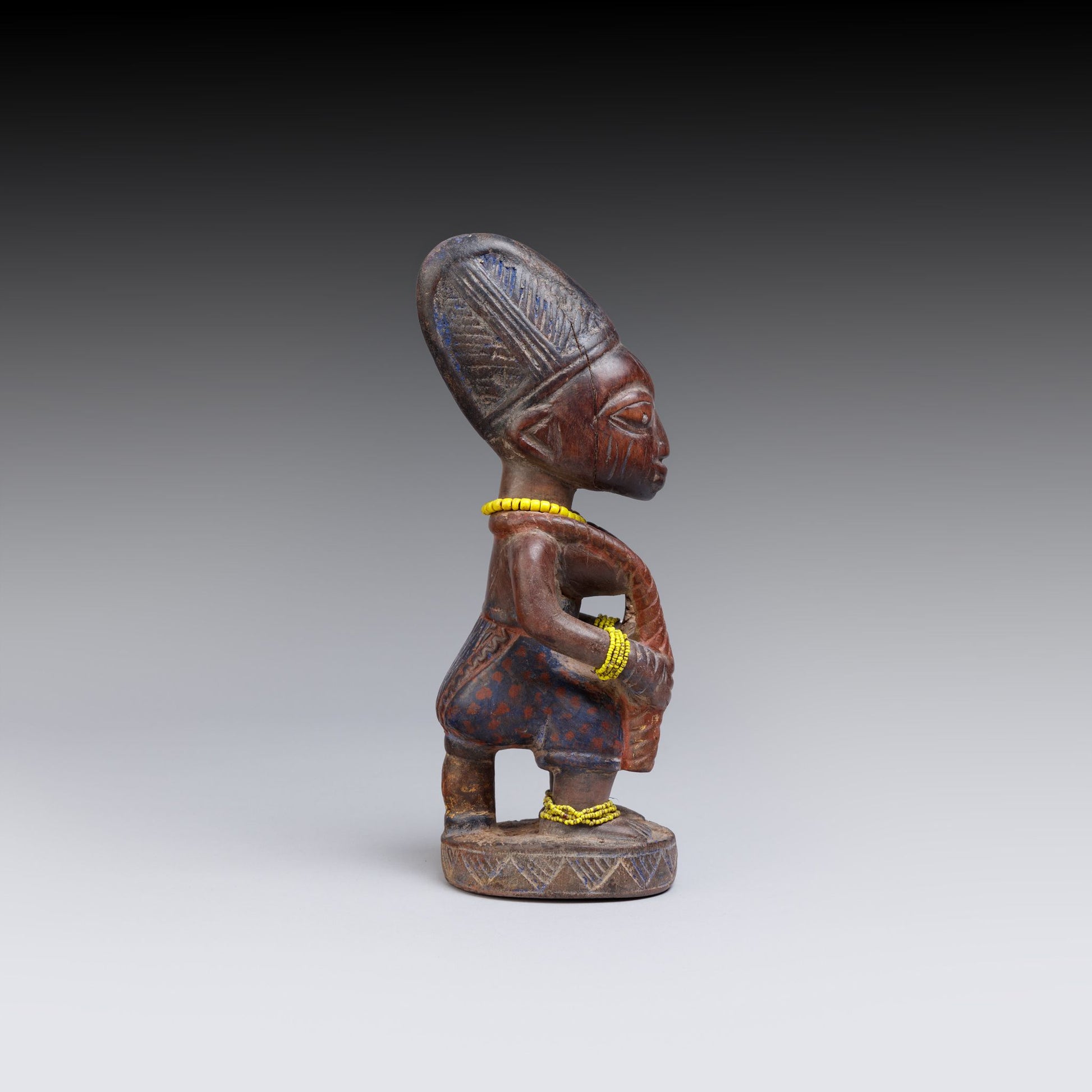 Wooden figurine with intricate carvings on a gray background